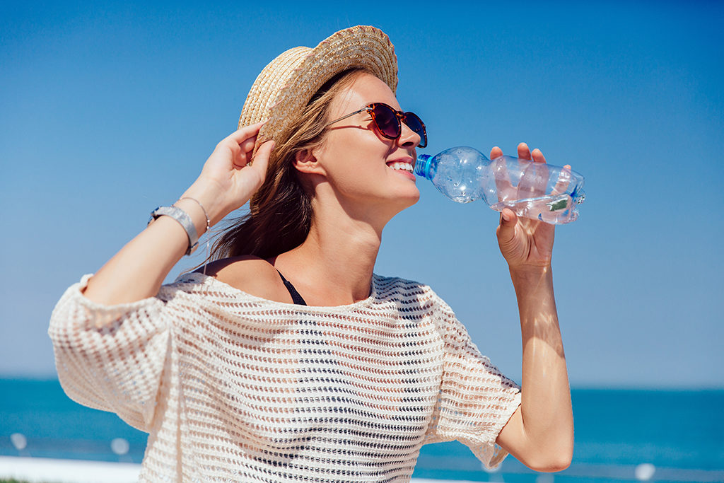 happy-pretty-girl-sunglasses-drinking-clear-water-during-walking-quay