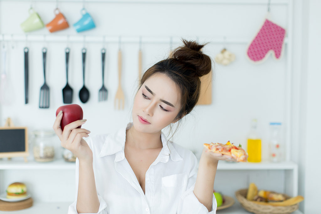 woman choosing between apple and pizza
